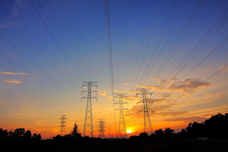 Galvanized steel transmission towers at golden hour for overhead power lines